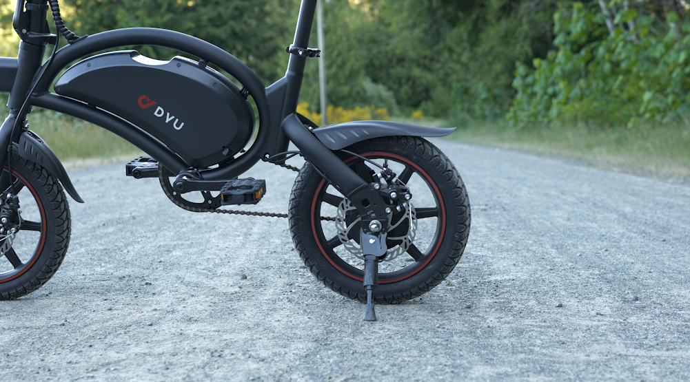 DYU D3F electric bike in an urban city landscape, showcasing its compact foldable design for easy commuting in 2024.